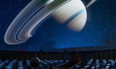 Der majestätische Saturn mit seinen Ringen füllt die Kuppel des Planetariums. Die leeren Sitze warten auf Besucher, die sich auf eine faszinierende Reise durch das All begeben.