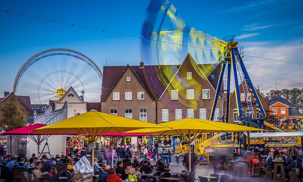 Beleuchtete Fahrgeschäfte und ein belebter Gastronomiebereich auf der Rathauskirmes in Meppen.